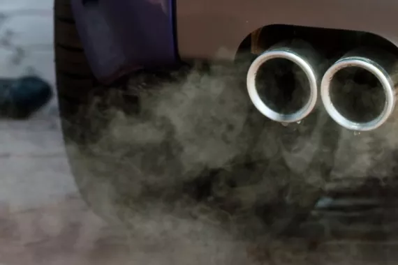 Close-up view of a car's exhaust pipes releasing carbon monoxide